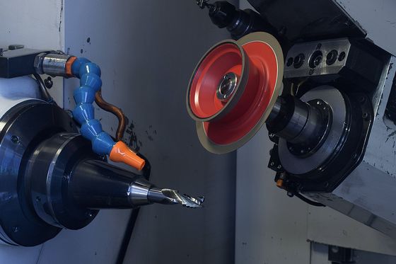 Werkzeugschleifmaschine im Eingriff, rote Schleifscheibe an einem eingespannten Hartmetallwerkzeug.